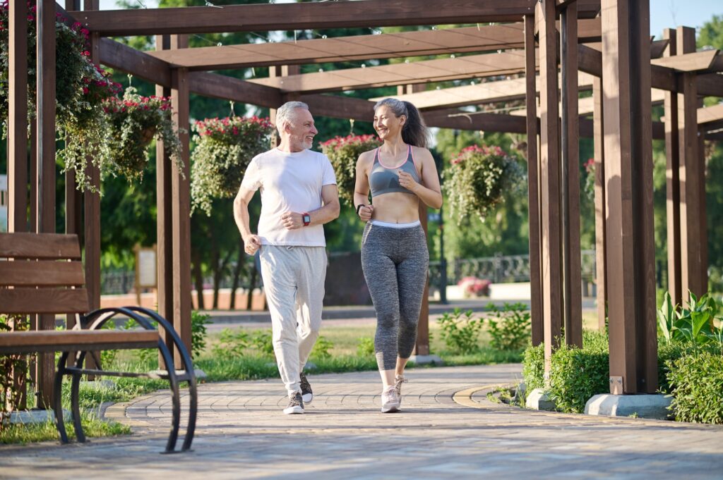 A mature couple running in the park and looking contented